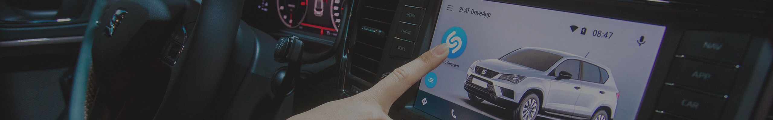 Finger touching the screen inside of a SEAT model with Shazam and SEAT DriveApp technology