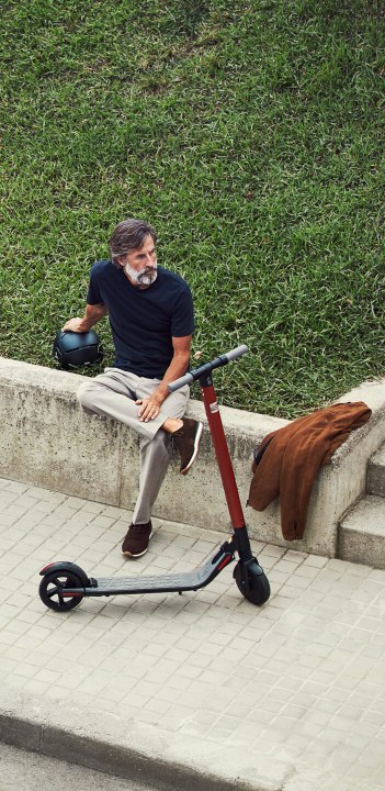 SEAT eXS KickScooter urban mobility solution powered by Segway - Man walking next to Tarraco large SUV