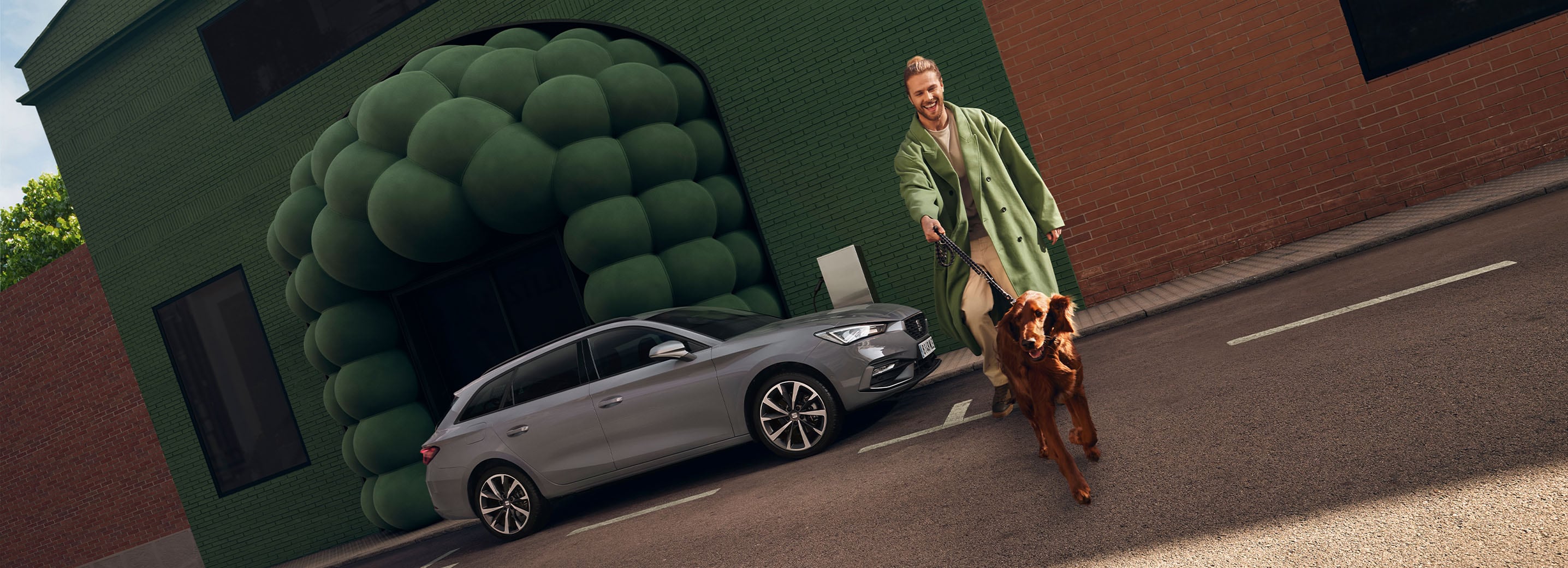 grey seat leon sportstourer and headlights with dynamic turn signals function There is an individual walking nearby dressed in the same colours as the background.
