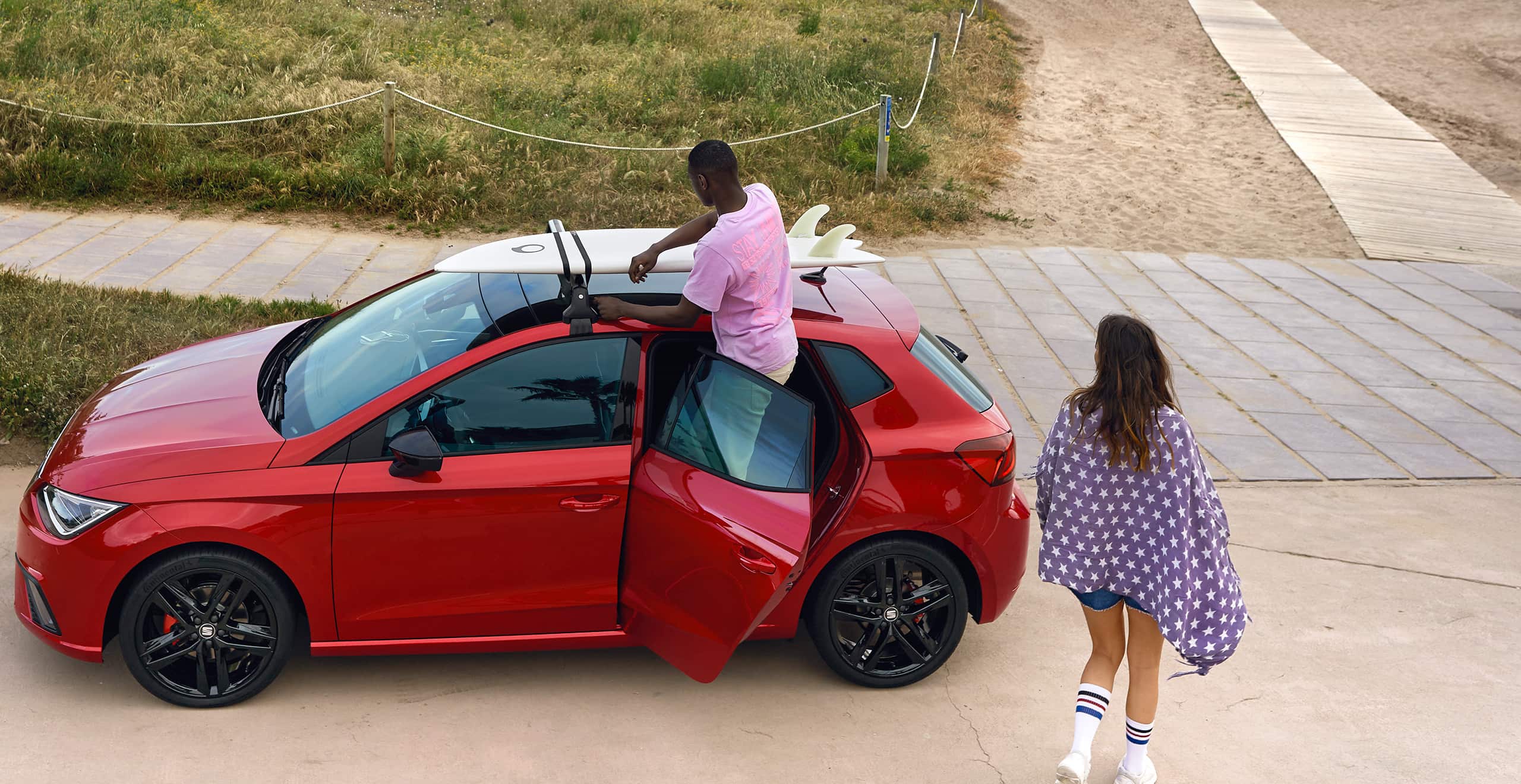 Man installing a surf rack on the SEAT Ibiza desire red colour 