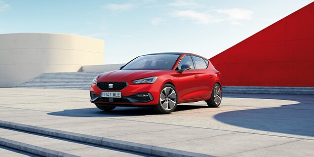red seat leon parked against a modern urban background, showcasing fuel economy and low emissions for environmentally conscious drivers.