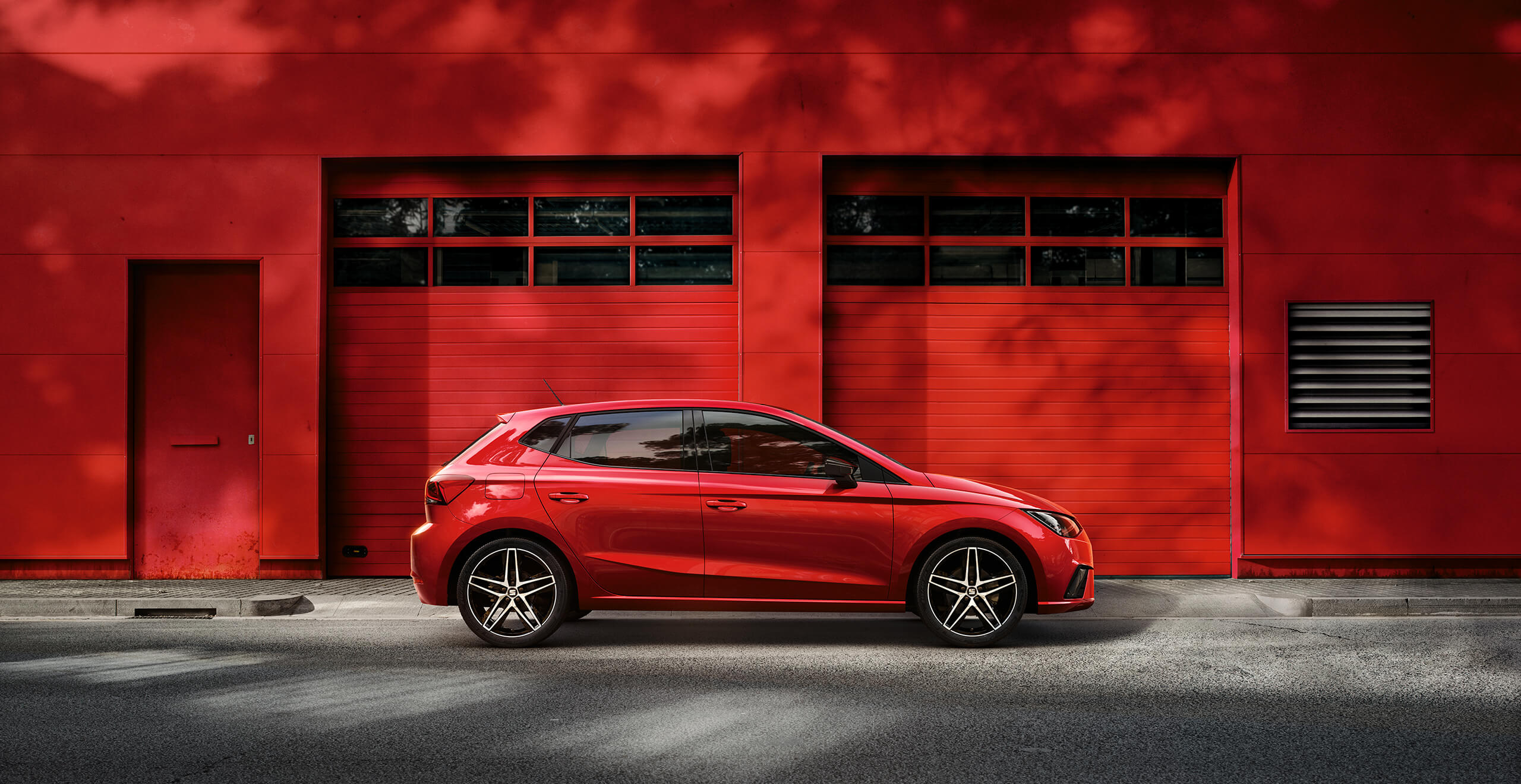 SEAT new car services maintenance independent garages – Red SEAT Ibiza city car hatchback parked in front of a red garage wall